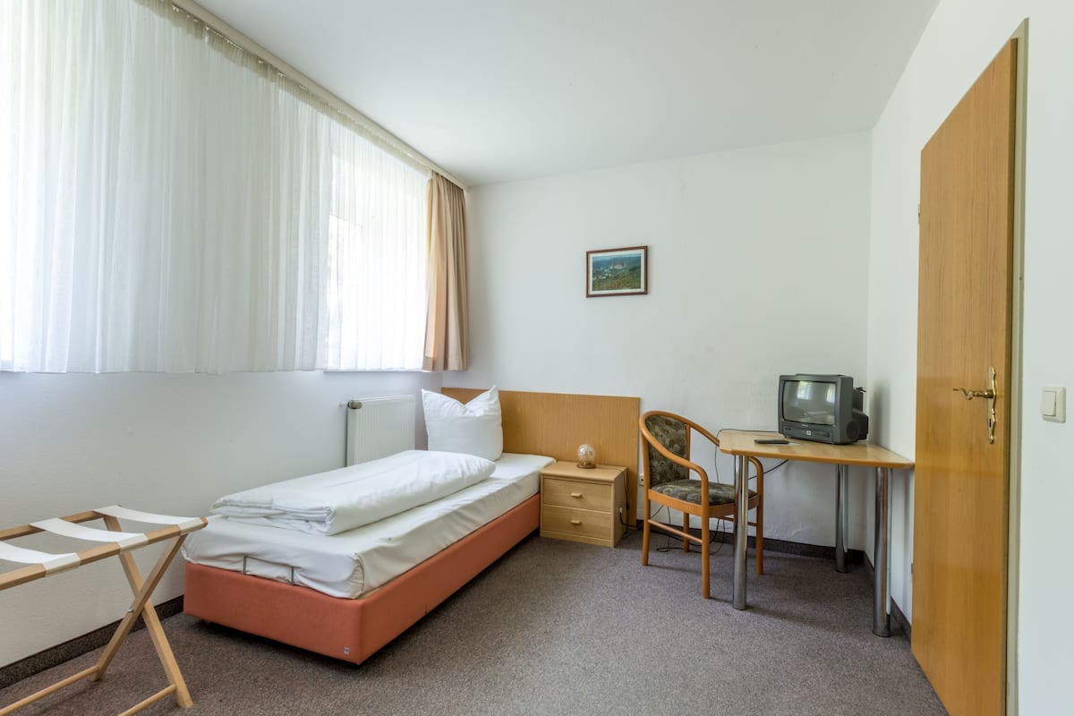 Une chambre à coucher comprenant un lit, un bureau, une chaise, une table de chevet et un téléviseur.