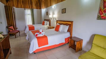 A hotel room with two beds, a wooden ceiling, a green chair, and a small wooden table.