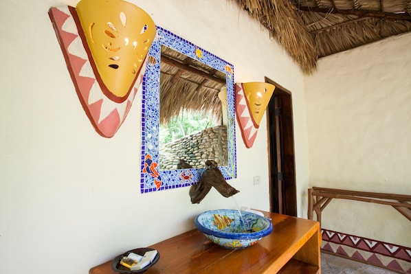 A room with a wooden bench, a tiled wall with a mosaic border, and a hanging cloth. - Hotel Punta Teonoste Boutique Beachfront Resort (Tola)