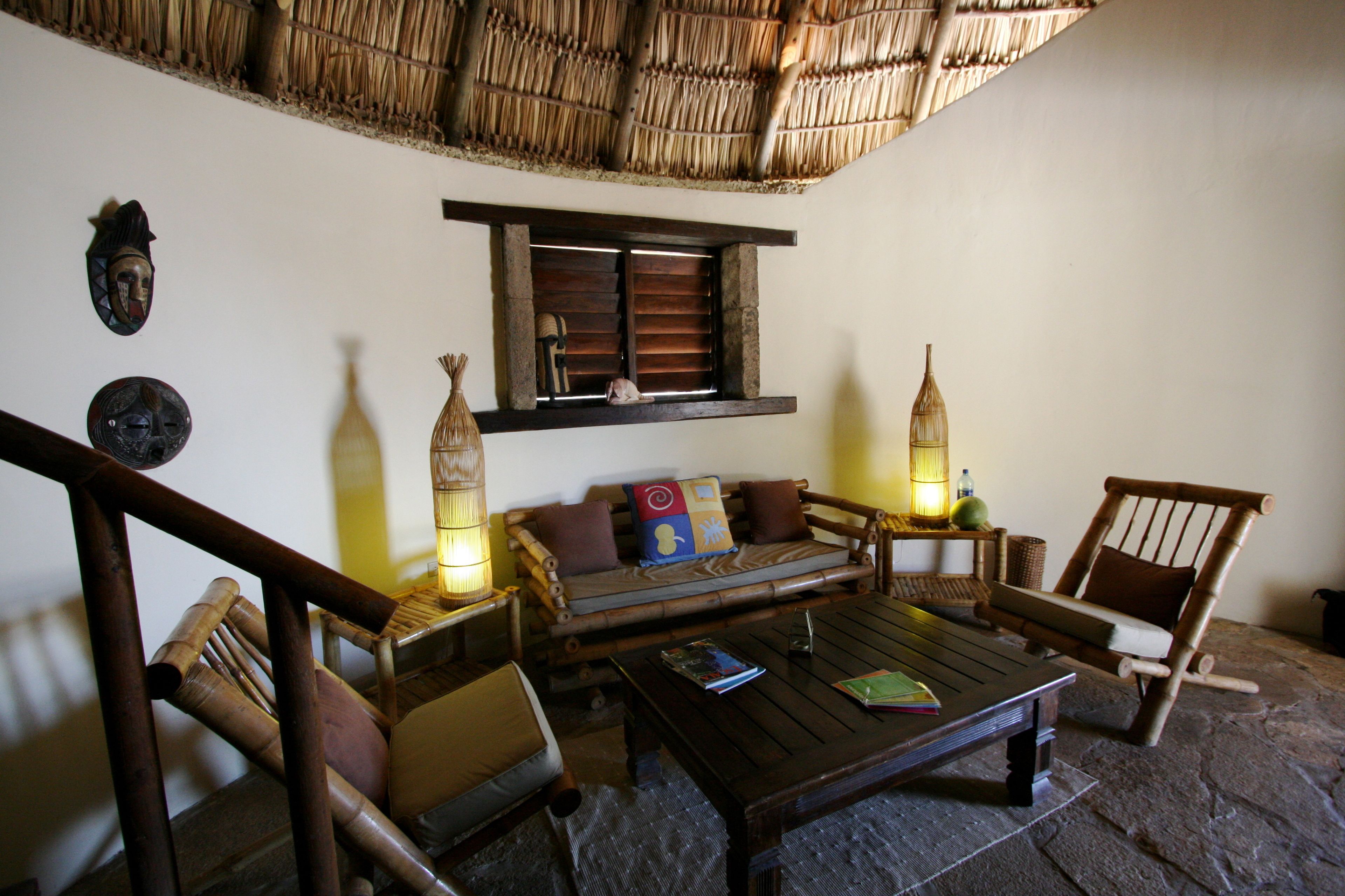 A traditional room with a thatched roof, wooden furniture, and a stone floor.