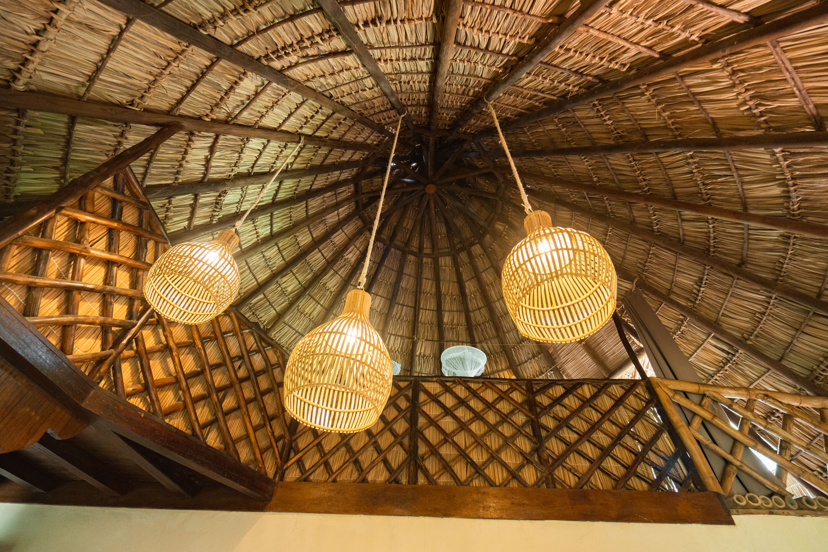 A thatched roof structure with hanging wicker lamps.