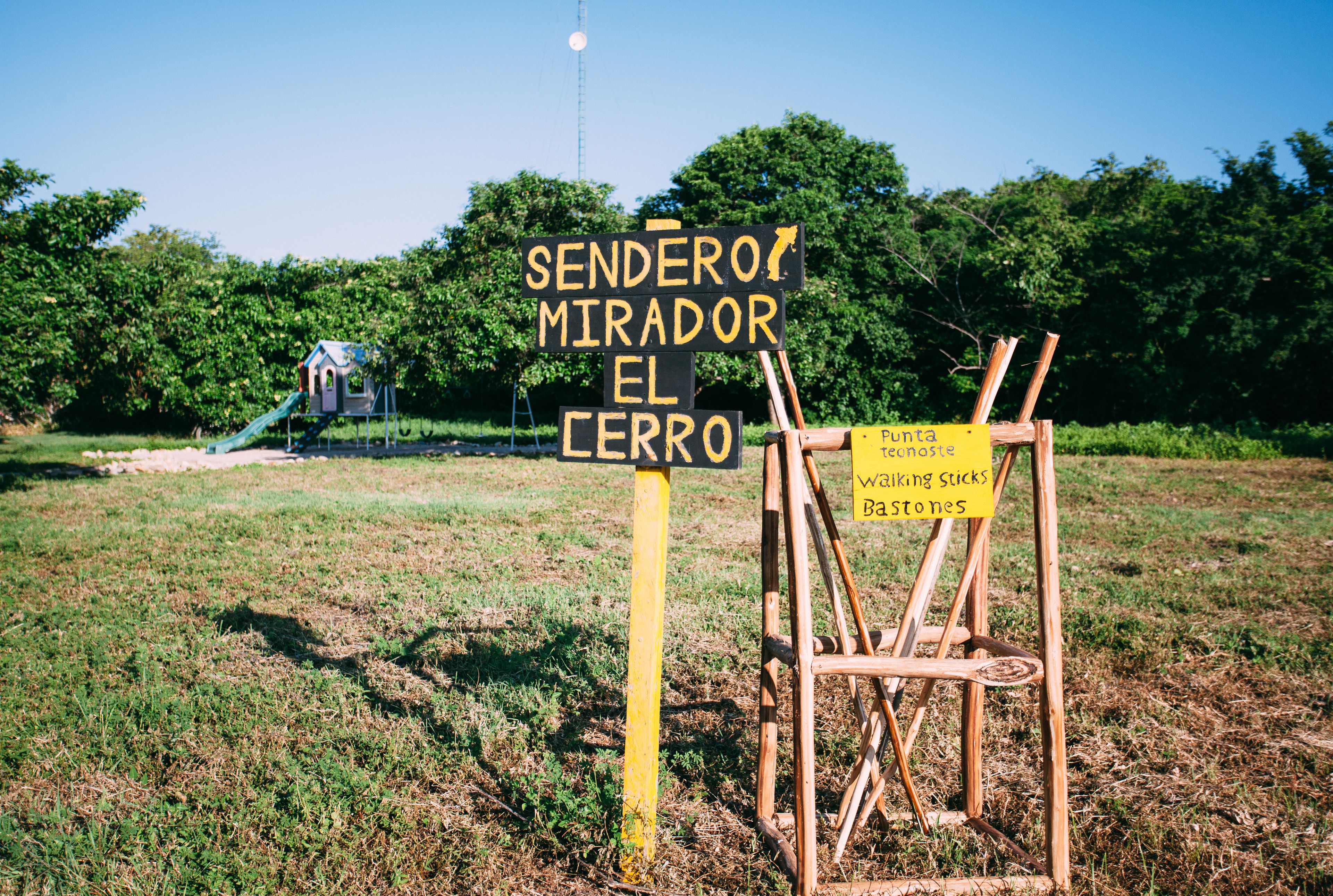 A playground with a slide and a sign that reads "SENDERO MIRADOR EL CERRO".