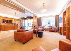 A spacious lobby with leather sofas, a reception desk, and a chandelier. - Hotel Mariahilf (Graz)