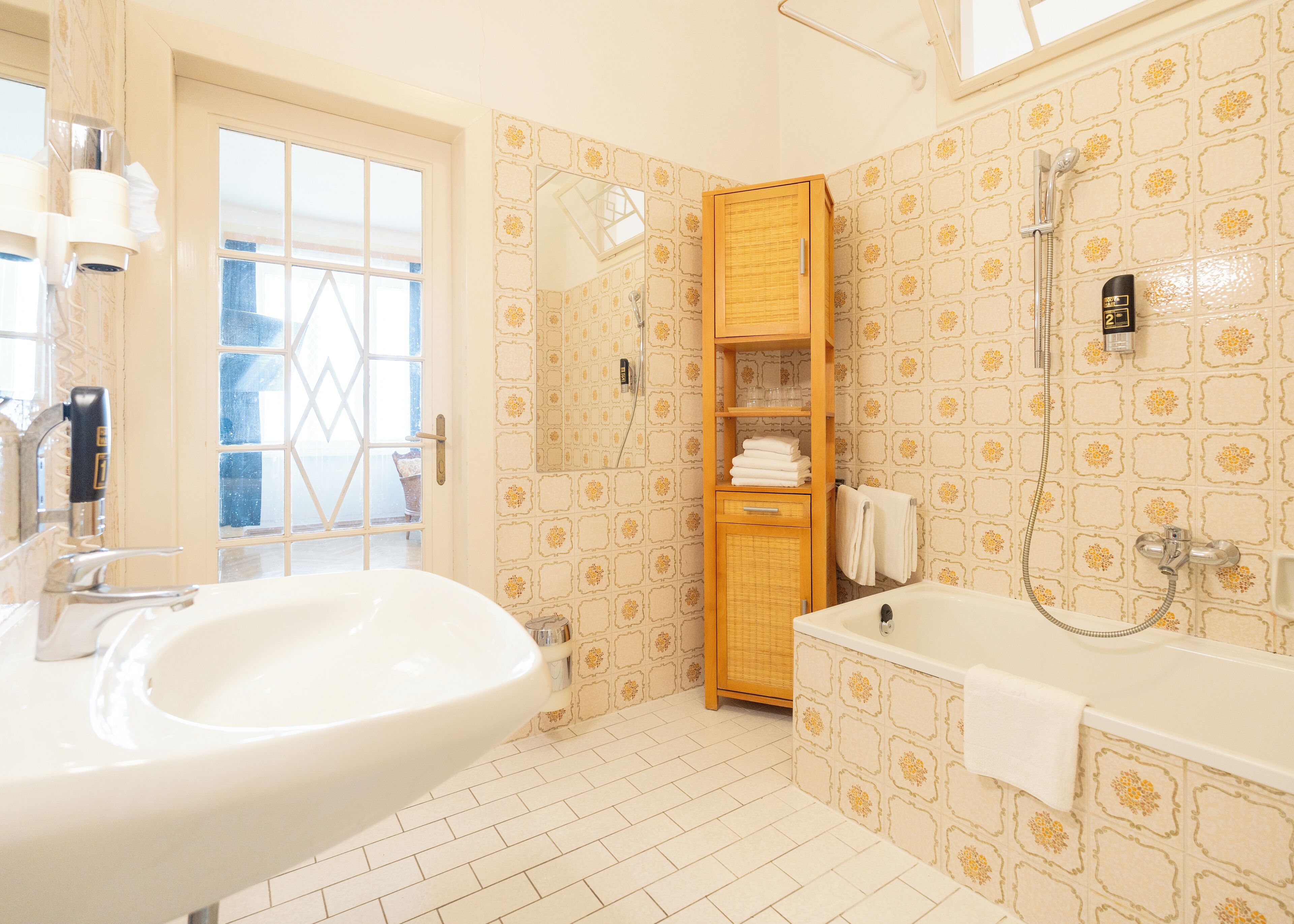 Ein Badezimmer mit einem großen Waschbecken, einer Badewanne, einer Dusche und einem Holzschrank mit Handtüchern.
