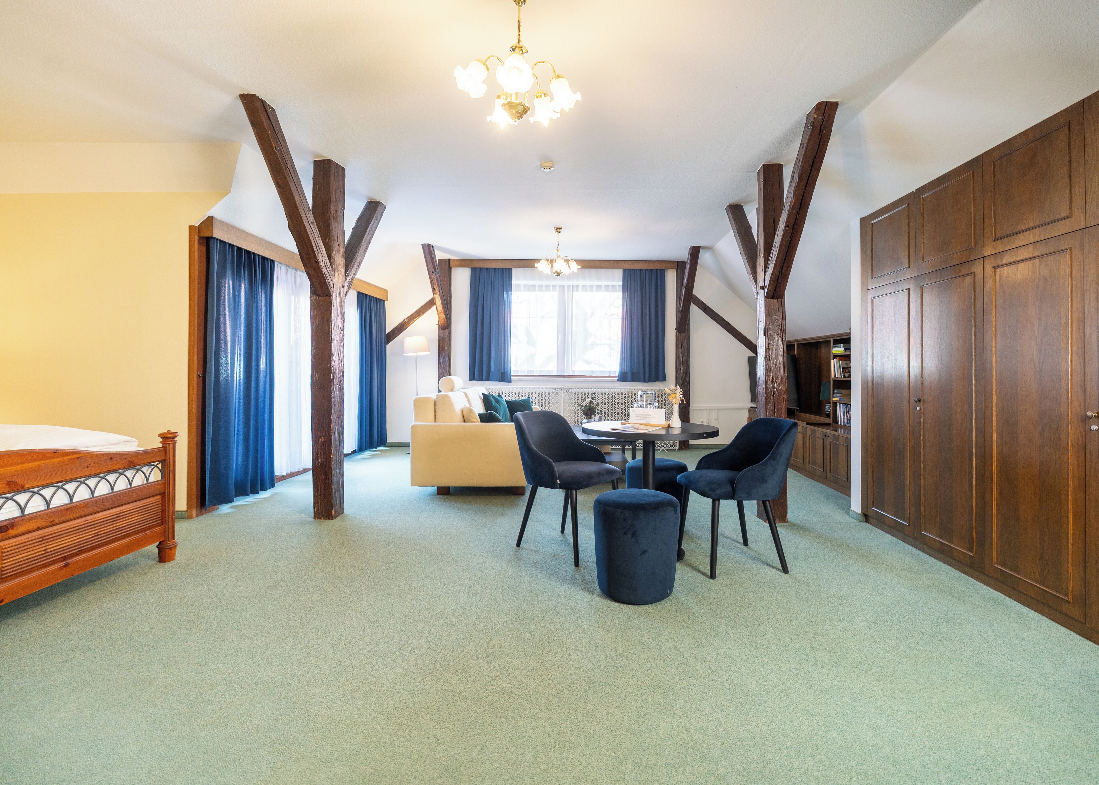 A room with a bed, a sofa, a dining table with chairs, and a wardrobe.