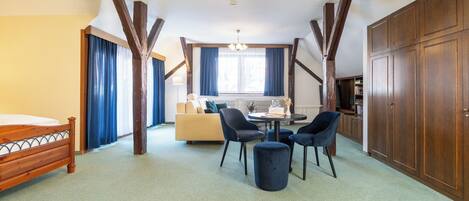 A room with a bed, a sofa, a dining table with chairs, and a wardrobe.