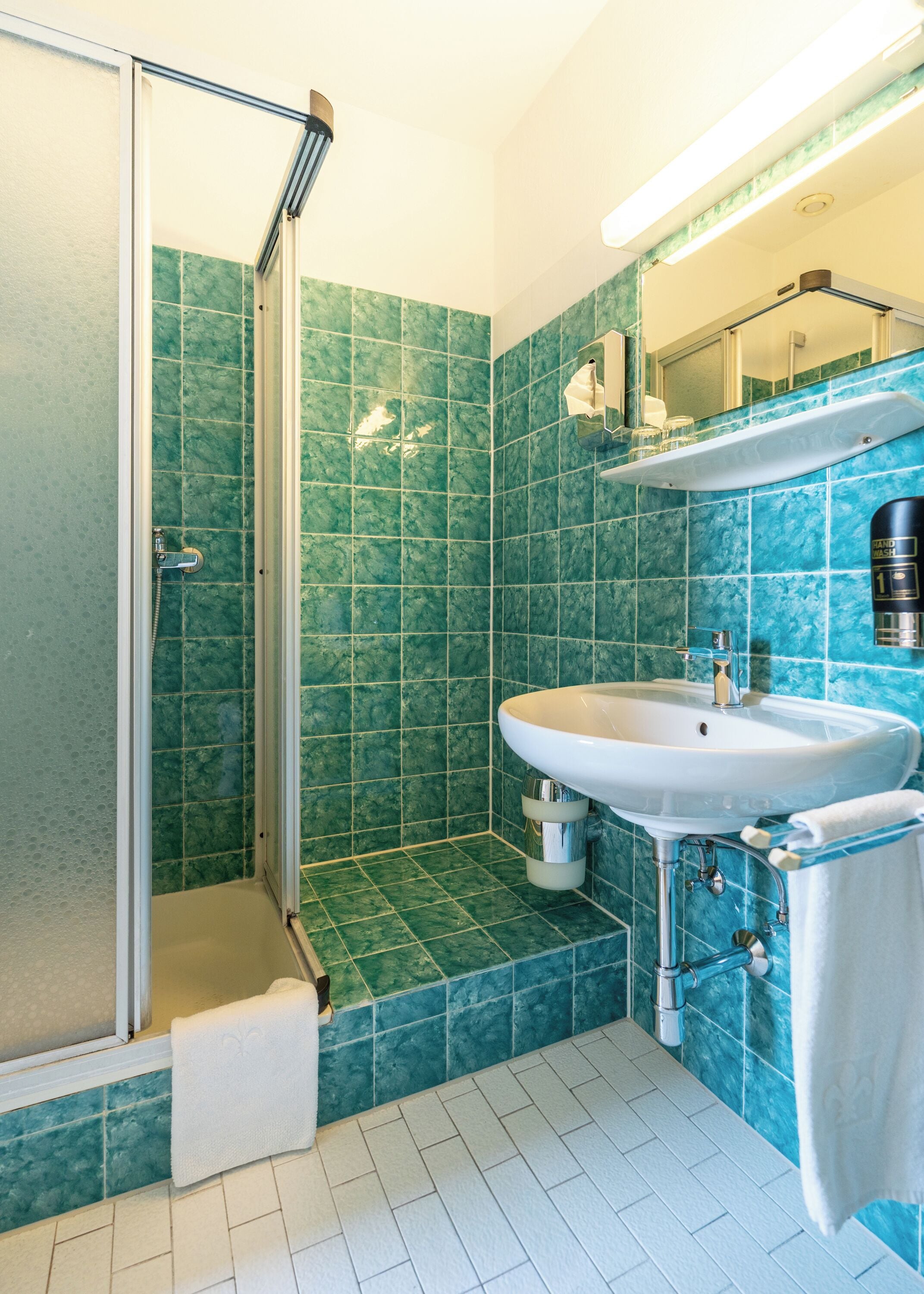 A bathroom with a shower, sink, and mirror.