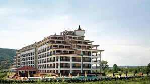 A multi-story hotel with balconies, a swimming pool, and outdoor seating. - Casablanca (Nessebar)