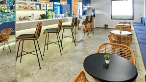 A modern bar area with wicker chairs, a counter with bar equipment, and a large screen. - Casablanca (Nessebar)