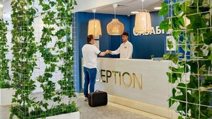 A reception area with a white reception desk, a blue wall with the word "RECEPTION" in gold letters, and hanging wicker lamps. - Casablanca (Nessebar)