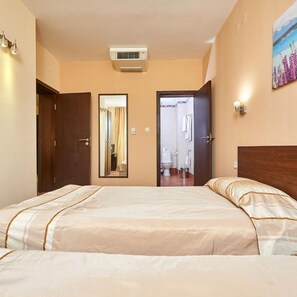 Ein Hotelzimmer mit Bett, Spiegel, Klimaanlage und einem durch eine geöffnete Tür einsehbaren Badezimmer.