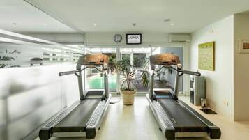 Une salle de sport équipée de deux tapis de course, d’une plante en pot et d’une horloge murale.