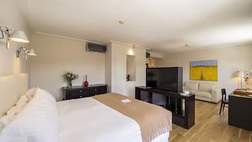 Una habitación de hotel con una cama grande, televisión, escritorio y sofá.