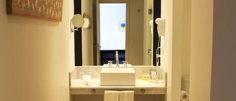 Une salle de bain d’hôtel équipée d’un lavabo, d’un miroir et d’un porte-serviettes.
