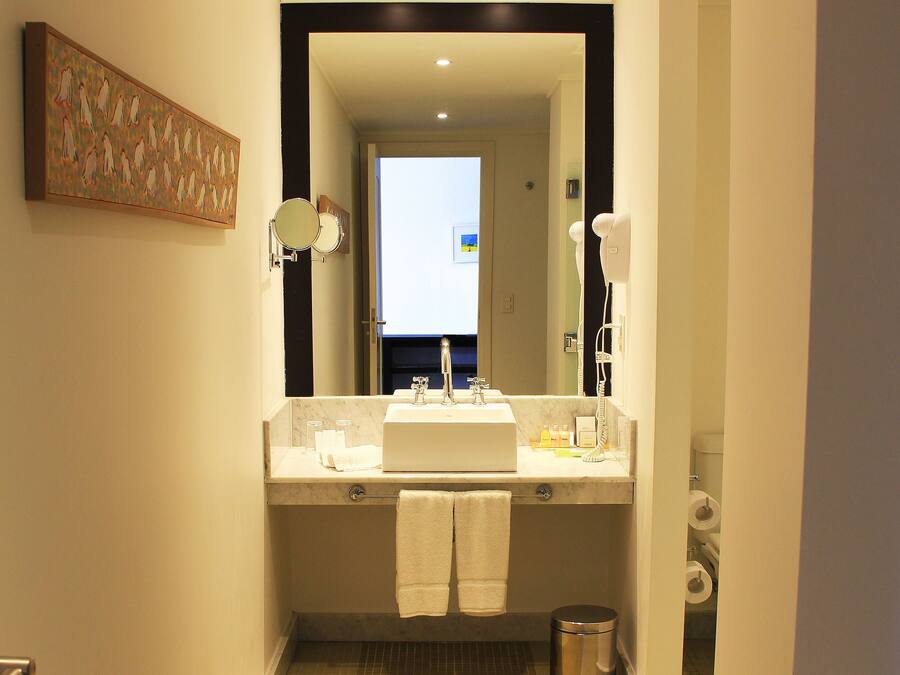 Un baño de hotel con lavamanos, espejo y toallero.