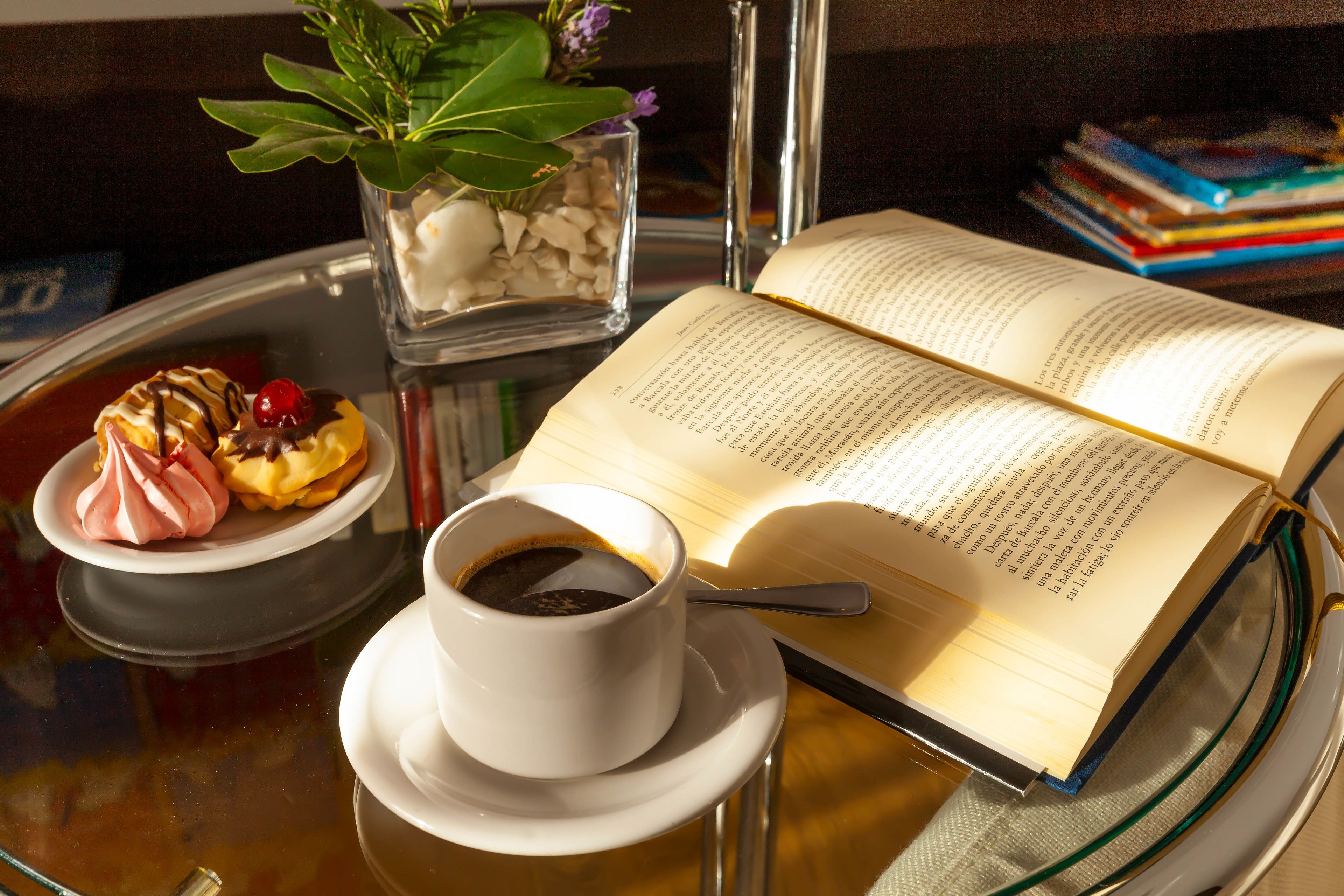 Een tafel met een boek, een kop koffie en een bord eten.