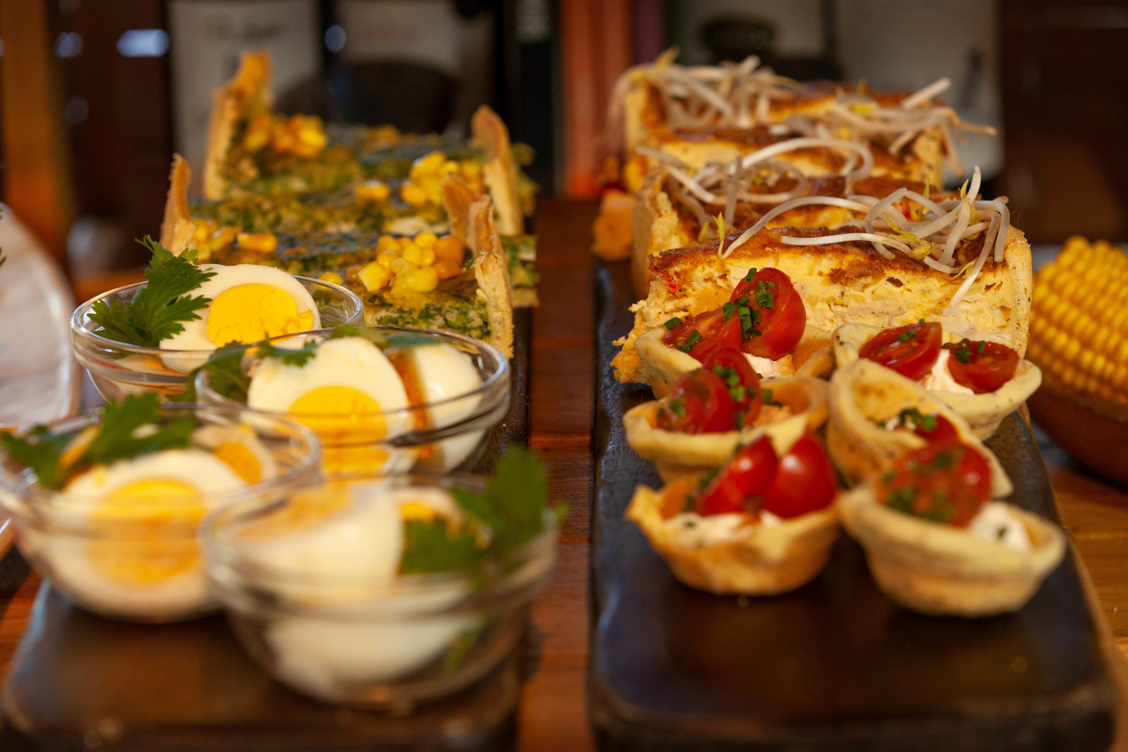 Diversos petiscos, incluindo ovos, milho e pequenas tartes, dispostos numa bandeja de servir.