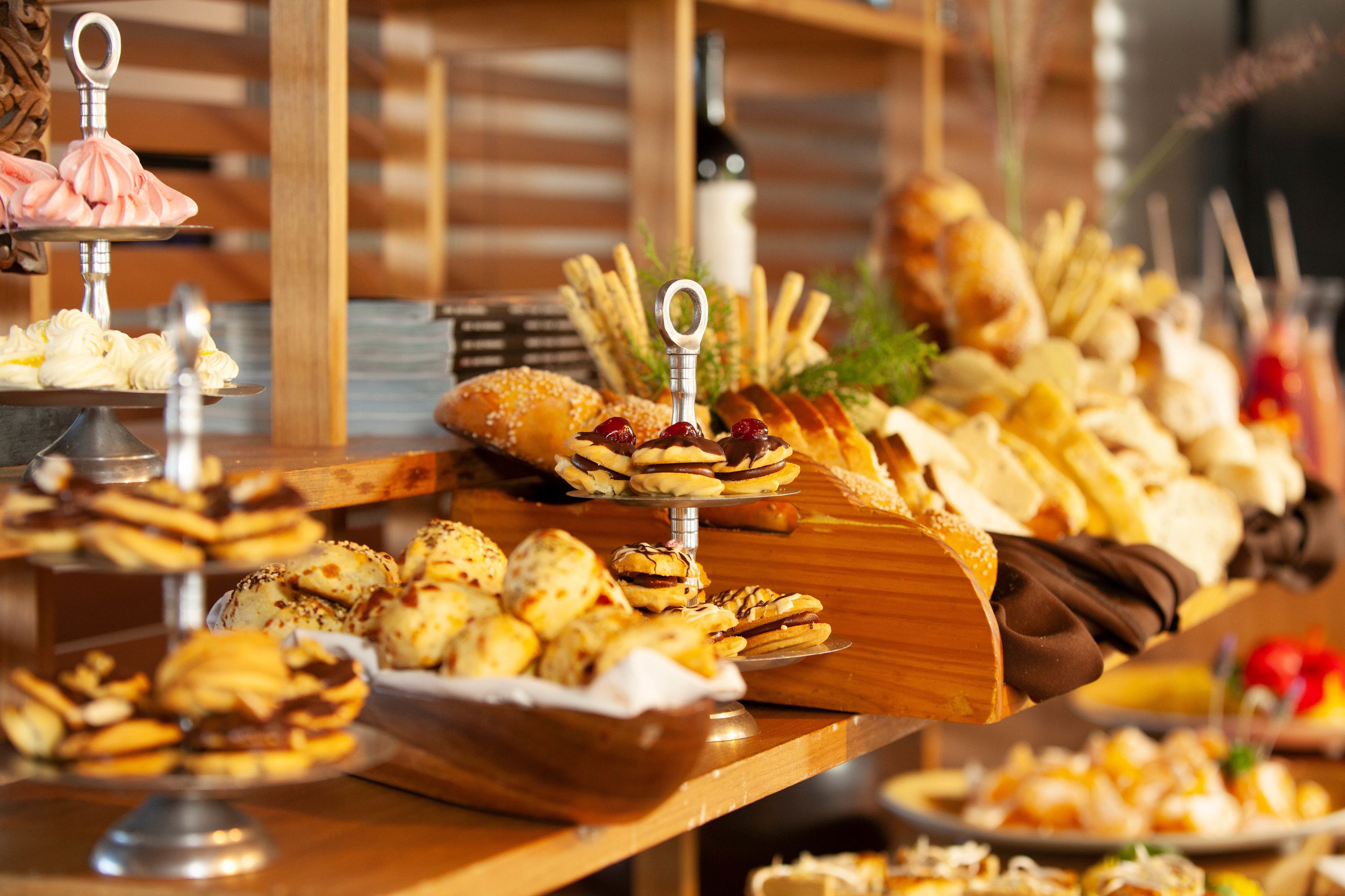 A buffet with various food items including pastries, sandwiches, and fruits.