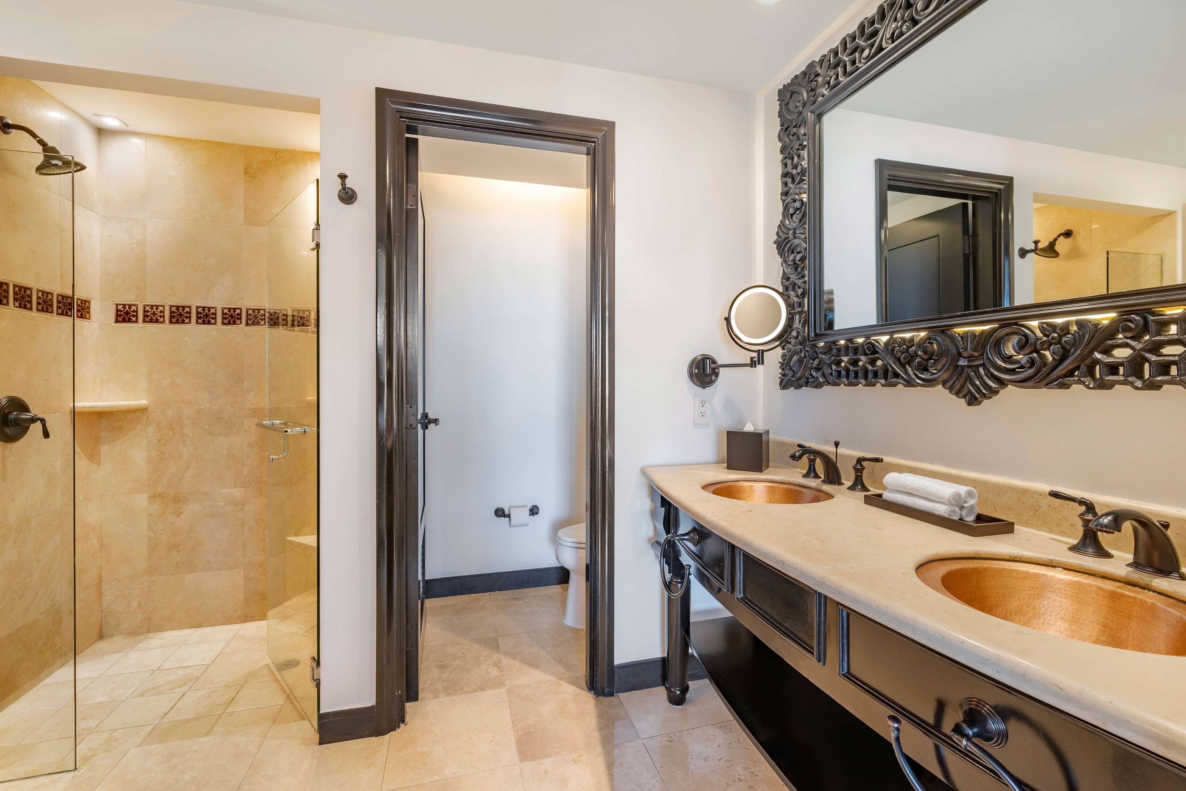 Un bagno moderno con doccia vetrata, due lavabi, uno specchio grande e un water.