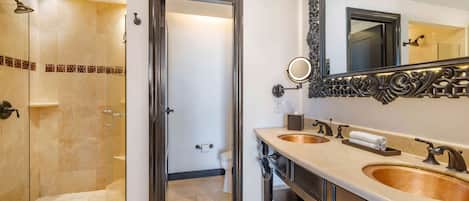 Un bagno moderno con doccia vetrata, due lavabi, uno specchio grande e un water.