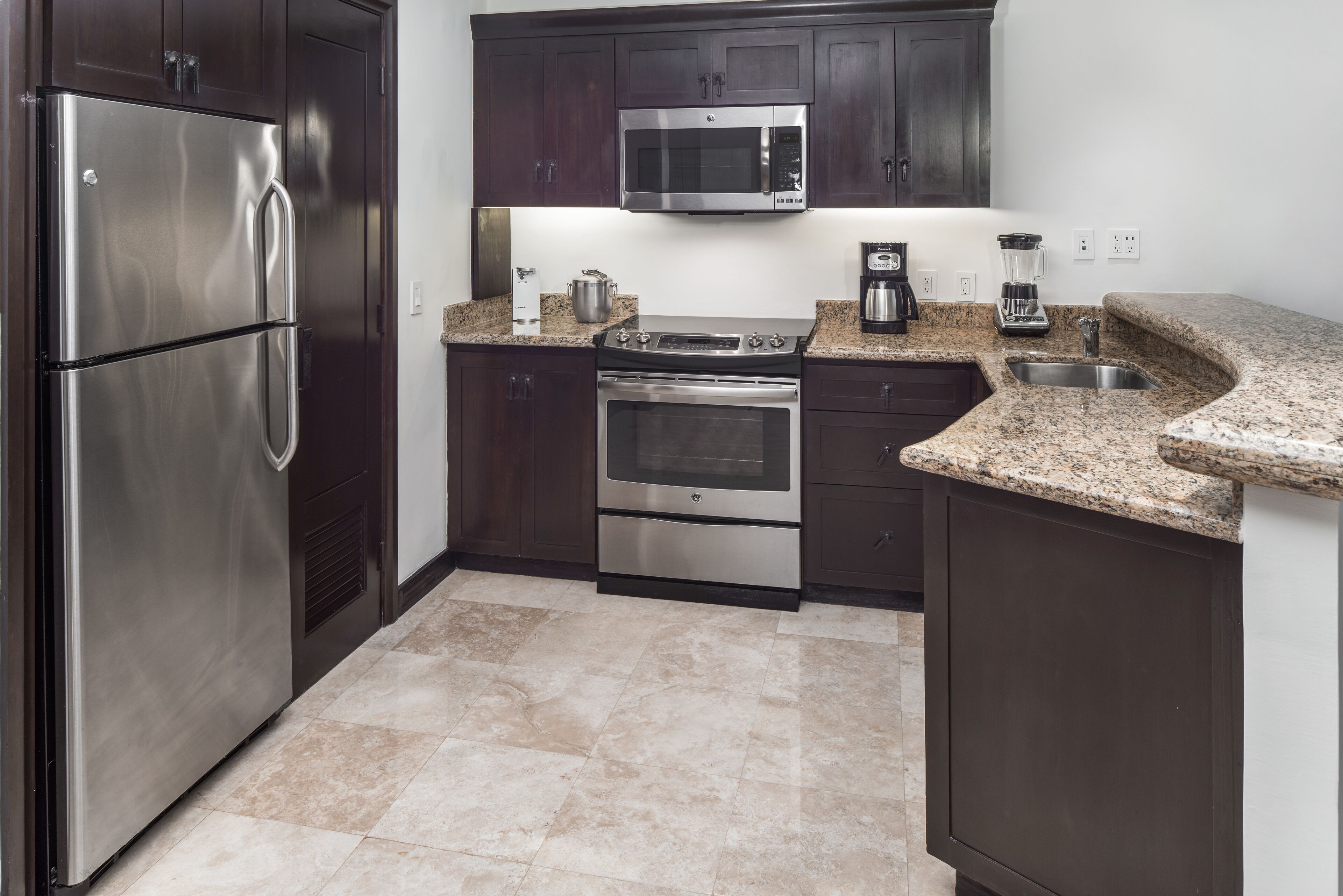 A modern kitchen with stainless steel appliances, granite countertops, and dark cabinetry.