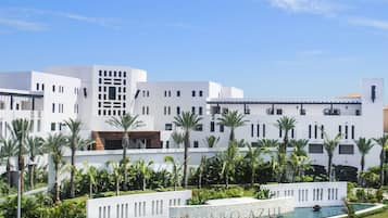 Un hotel moderno con arquitectura blanca, piscina y palmeras.