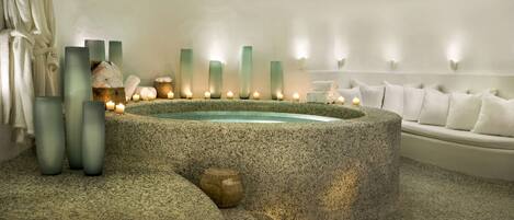 Un espace spa comprenant un bain en pierre, des bougies et des serviettes.