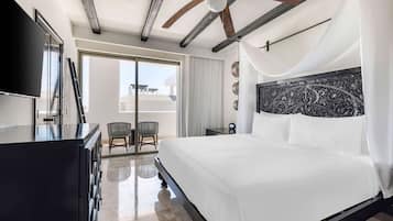 Habitación de hotel moderna con una cama grande, ventilador de techo, televisor de pantalla plana y balcón con vistas.