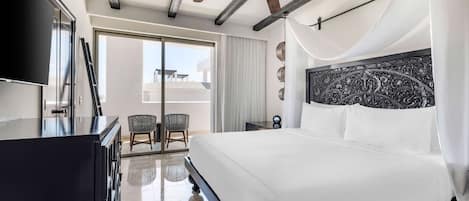 A modern hotel room with a large bed, a ceiling fan, a flat-screen TV, and a balcony with a view.