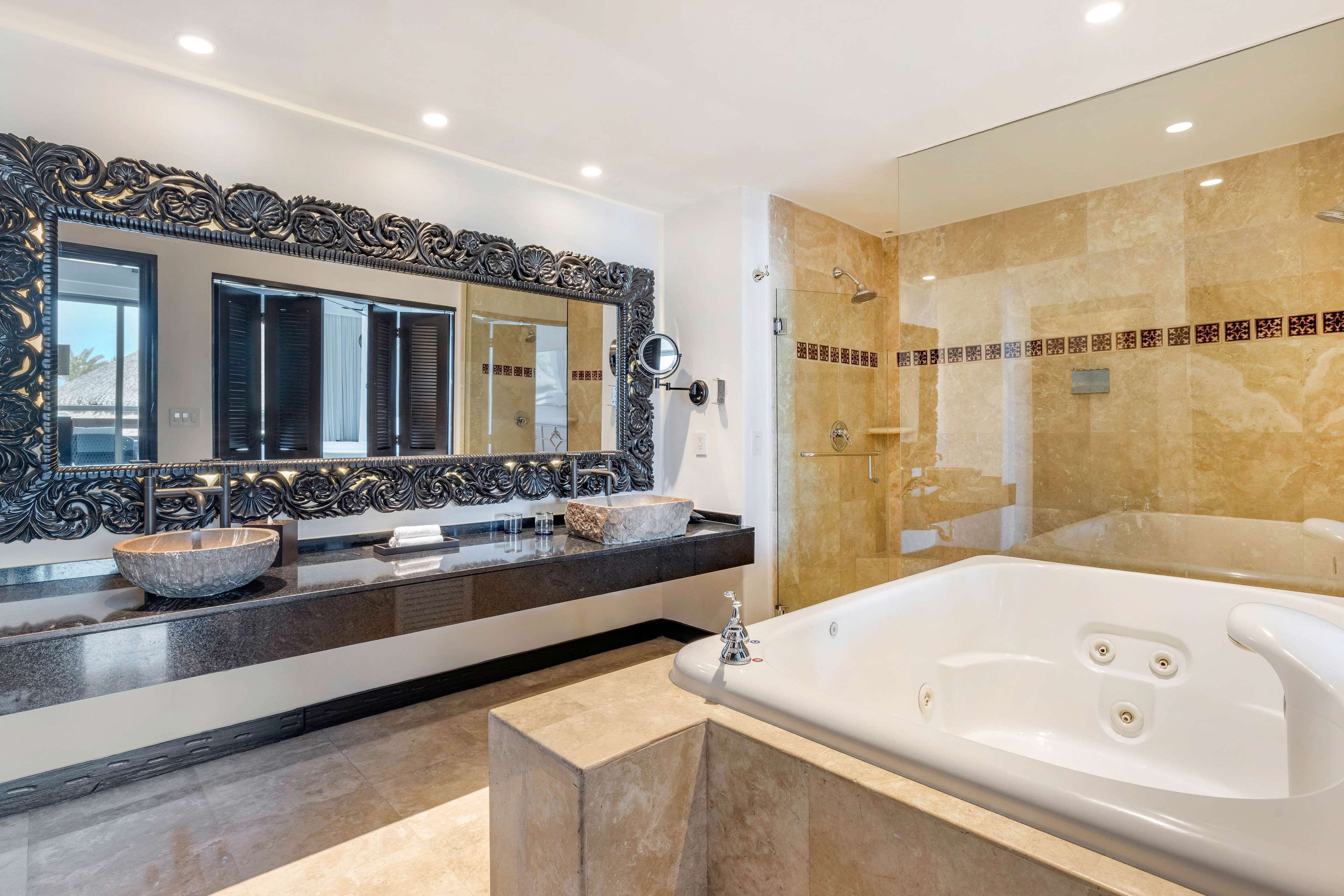 A modern bathroom with a large mirror, a bathtub, a vanity with a bowl sink, and a shower area.