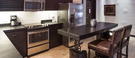 A modern kitchen with dark cabinetry, stainless steel appliances, and a central island with seating.
