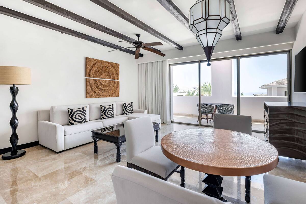 A modern living room with a white sofa, patterned cushions, a round coffee table, and a ceiling fan.