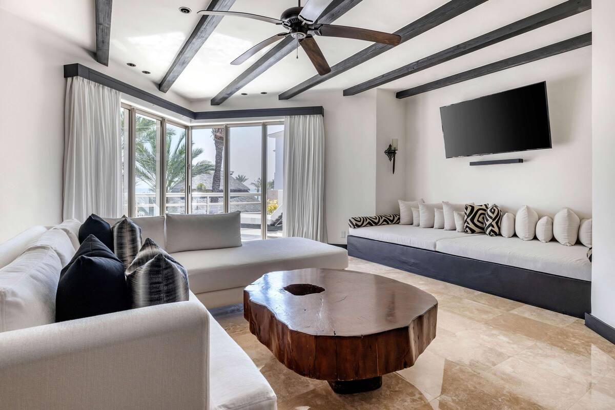 A modern living room with a ceiling fan, a large TV, a sofa, and a coffee table.