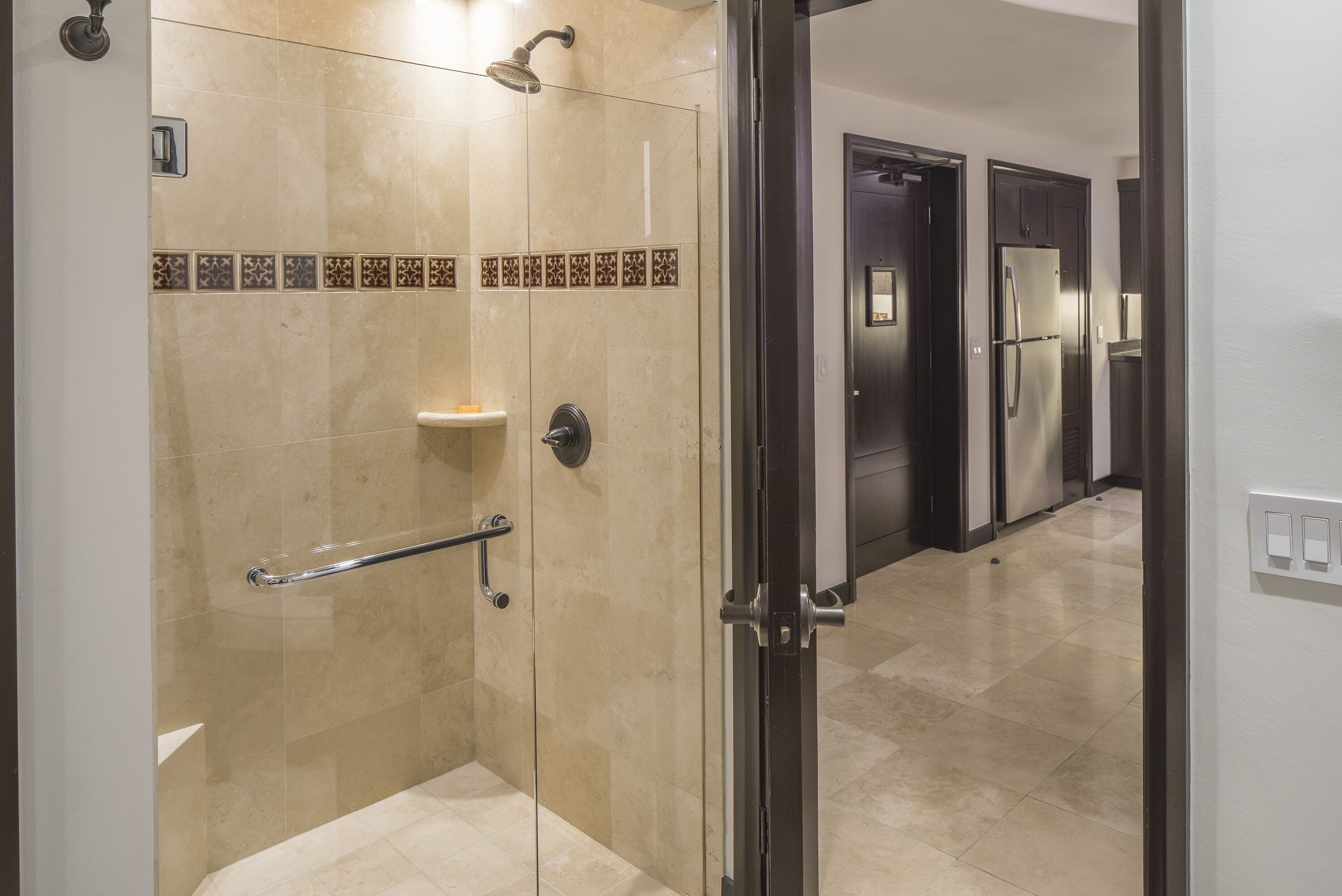 A modern bathroom with a shower, a handrail, and a tiled floor.