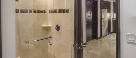 A modern bathroom with a shower, a handrail, and a tiled floor.