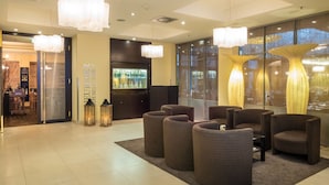 A lobby with a seating area, a bar, and a large window with a view. - Lindner Hotel Vienna Am Belvedere, part of JdV by Hyatt (Vienna)