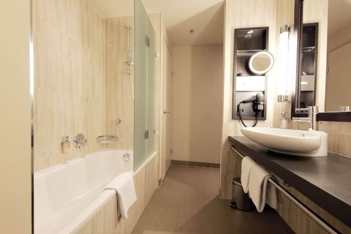 A modern bathroom with a bathtub, a sink with a mirror, and a shower area.
