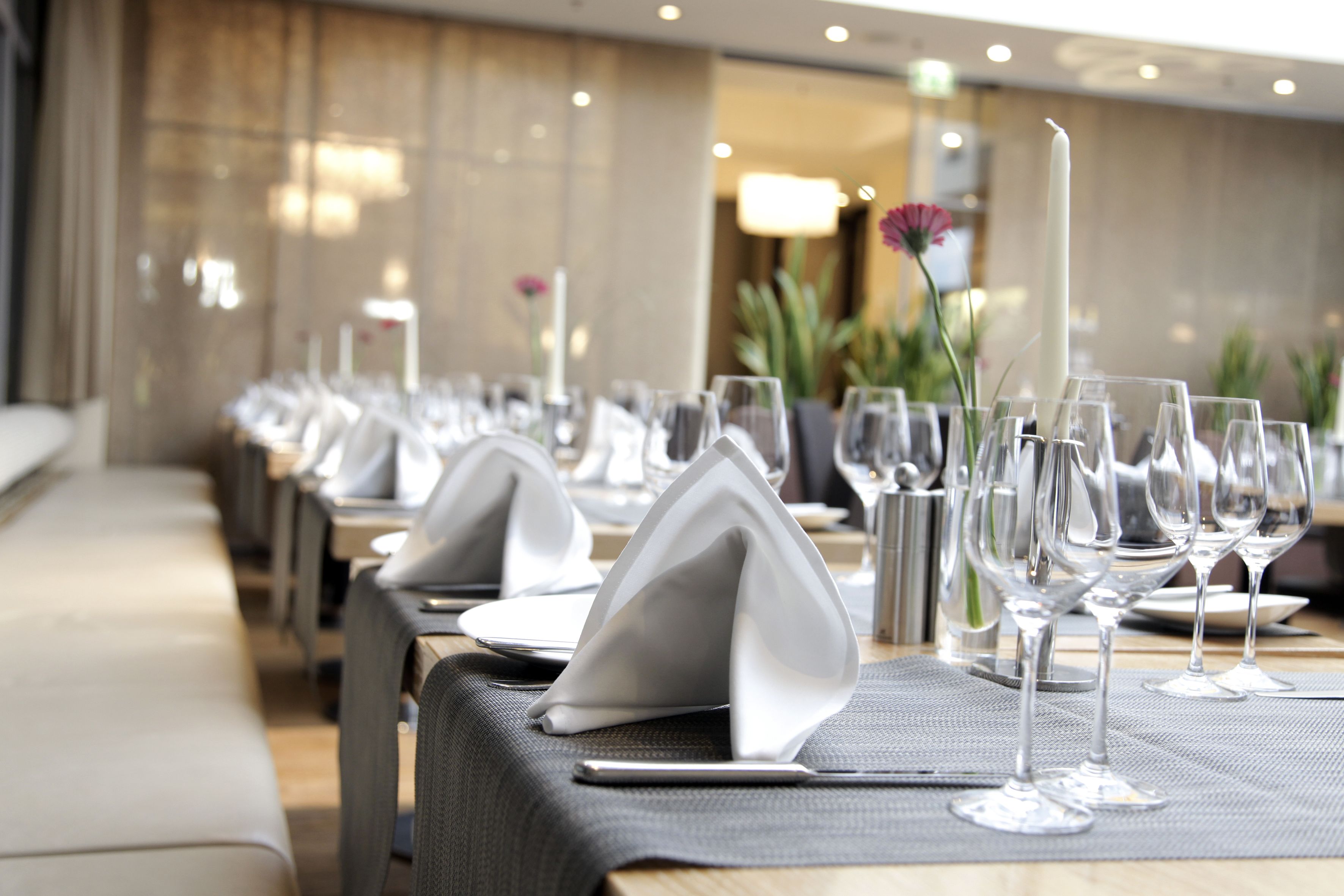 A restaurant setting with tables set for dining, featuring neatly arranged plates, glasses, and napkins.
