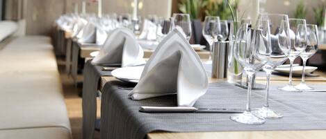 A restaurant setting with tables set for dining, featuring neatly arranged plates, glasses, and napkins.