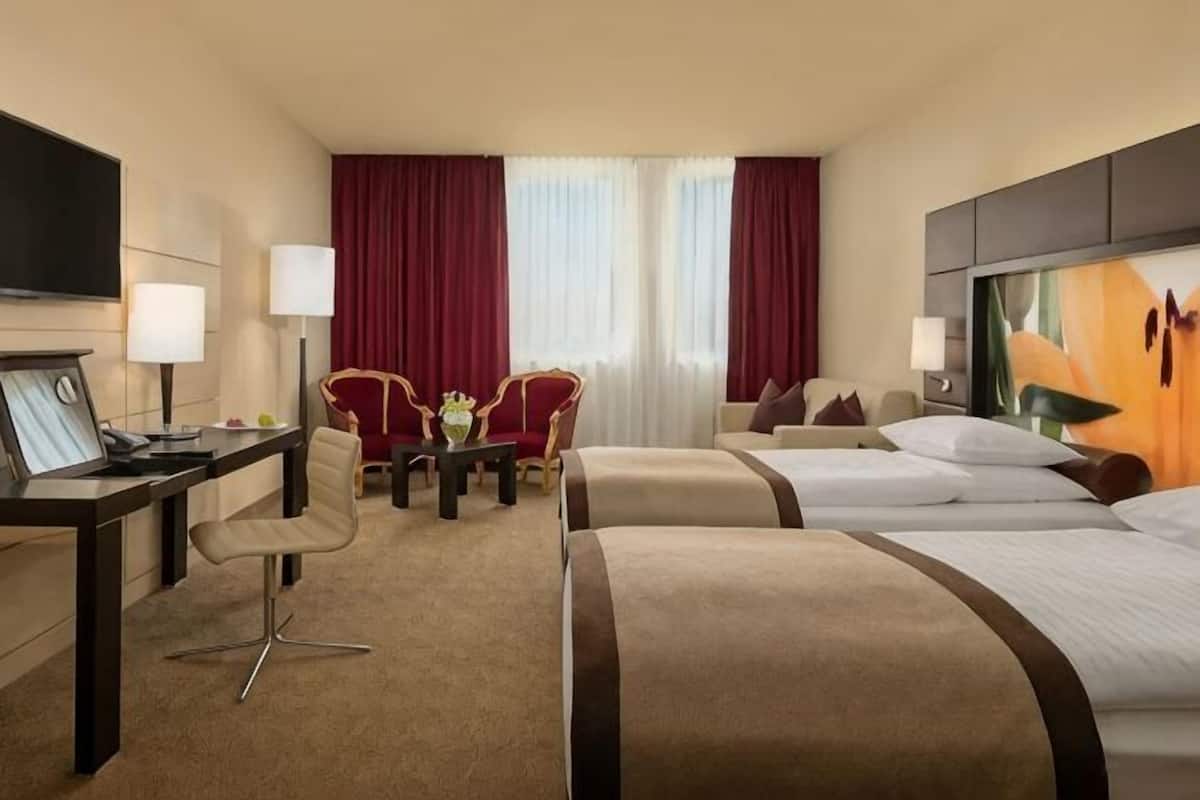 Una habitación de hotel con escritorio, dos sillas, una cama y un televisor.