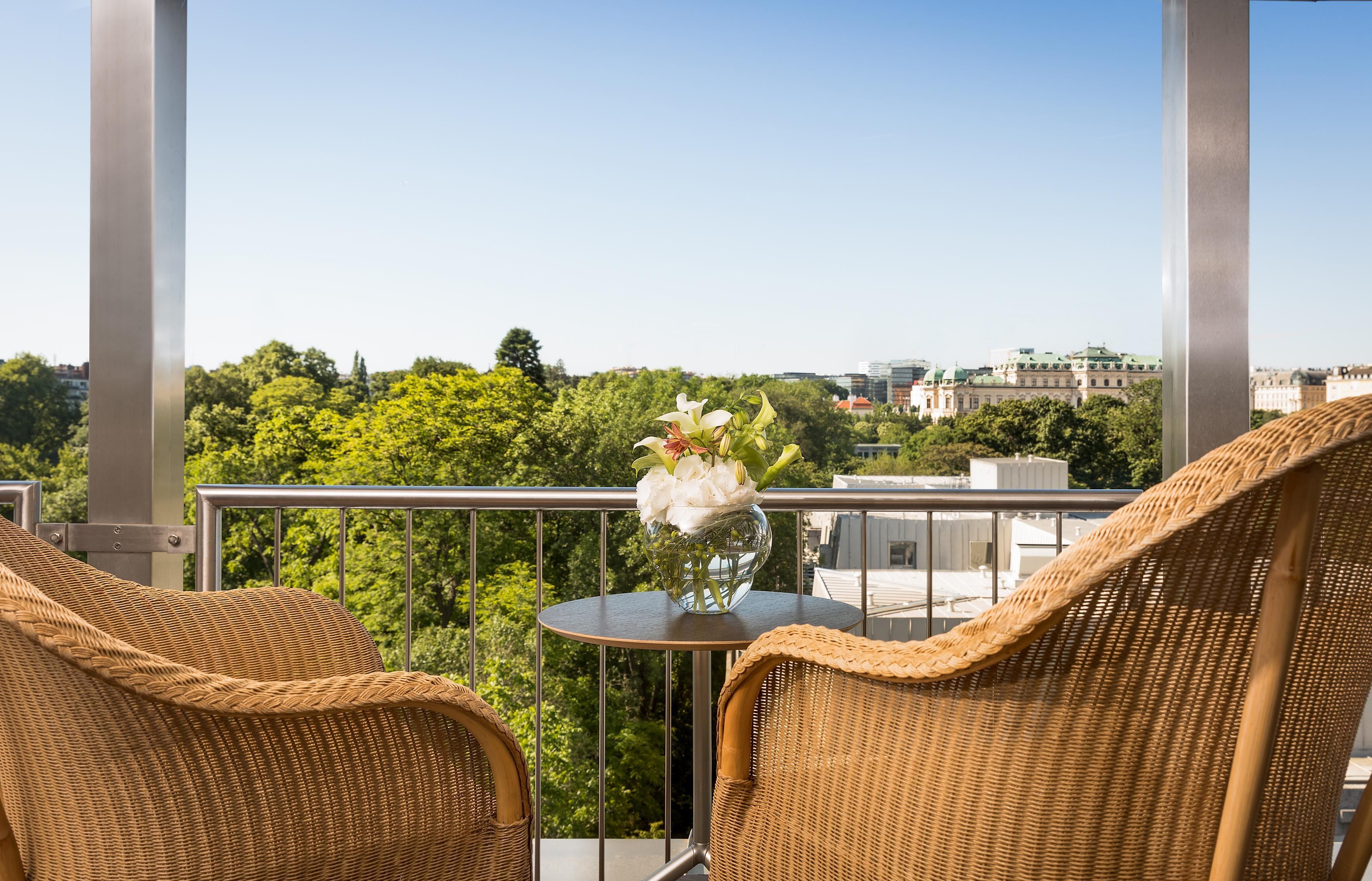 Ein Balkon mit Korbstühlen, einem kleinen Tisch und einem Blumenstrauß.