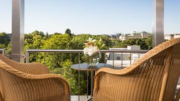 Ein Balkon mit Korbstühlen, einem kleinen Tisch und einem Blumenstrauß.