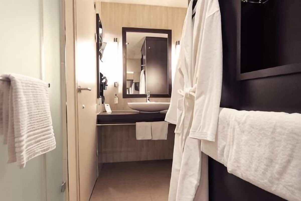 Un baño moderno con un espejo grande, un lavabo y un perchero para toallas.