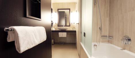 A modern bathroom with a bathtub, a sink, and a mirror. There is a towel rack with a towel hanging on it.