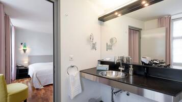 Un baño de hotel moderno con un espejo grande, un lavamanos y un inodoro.
