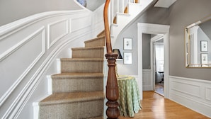 A staircase with a wooden handrail, carpeted steps, and a green table with a floral tablecloth in the background. - Isaiah Jones Homestead Bed & Breakfast (Sandwich)