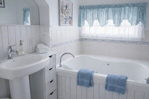 A bathroom with a white sink, a bathtub, and a window with a blue checkered curtain. - Isaiah Jones Homestead Bed & Breakfast (Sandwich)