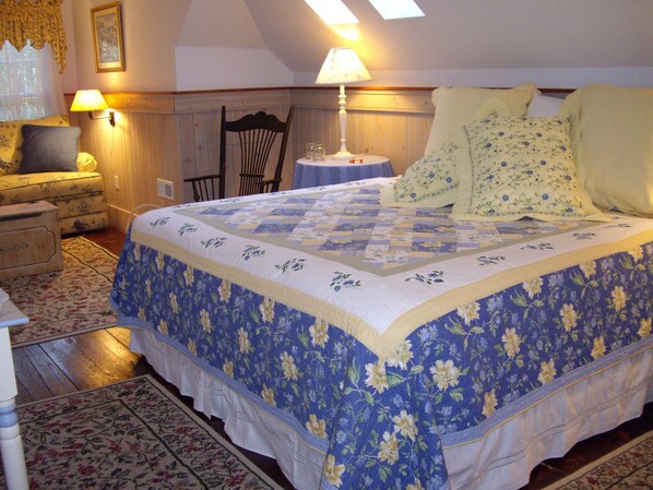 A bedroom with a large bed, a nightstand, a chair, a small table, and a lamp. - Isaiah Jones Homestead Bed & Breakfast (Sandwich)