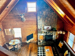 L’intérieur d’une cabane en rondins, avec une cheminée en pierre, une table à manger en bois et une tête de cerf accrochée au mur.