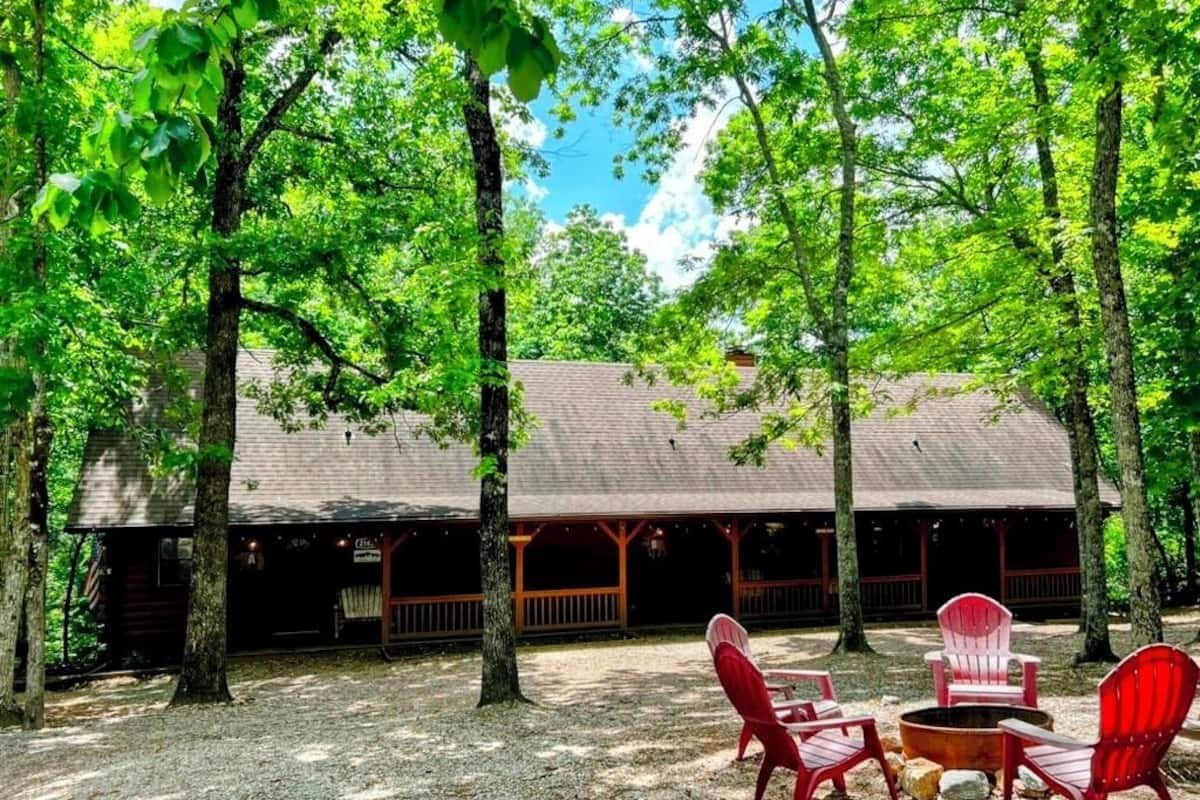 A cabin with a covered porch, outdoor seating, and a fire pit.